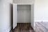 Spacious walk-in closet with open double doors and elegant wood flooring, perfect for organized living.