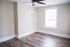 Bright and airy room with modern wooden flooring, built-in shelves, and a large window providing natural light.