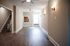 Bright and inviting living area with elegant hardwood floors, modern ceiling fans, and warm wall sconces, leading to an open-concept kitchen.