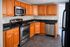Modern kitchen with warm wooden cabinets, sleek stainless steel appliances, and elegant black countertops, perfect for culinary enthusiasts.