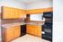 Inviting kitchen with warm wood cabinetry, sleek black appliances, and elegant countertops, ideal for culinary creativity.