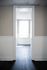Inviting hallway with elegant dark wood flooring leading to a bright room filled with natural light through a large window.