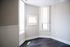 Bright corner room with large windows and sleek dark flooring, offering abundant natural light and modern appeal.