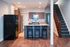 Modern kitchen with granite countertops, sleek appliances, and a cozy breakfast bar with three chairs. Elegant staircase adds charm to the open space.