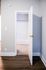 Inviting interior with a modern open door leading to a warmly lit space, highlighting sleek hardwood floors and contemporary design.