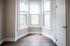 Bright room with elegant bay windows and sleek hardwood flooring, offering a serene view.