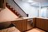 Elegant kitchen with granite countertops, wood cabinetry, and integrated stainless-steel appliances next to a stylish wooden staircase.