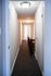 Bright and inviting hallway with modern lighting and plush carpet leading to open doors, showcasing elegant design and spacious layout.