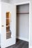 Sleek, open closet with mirrored white door and elegant dark wood flooring, perfect for modern living.