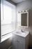 Bright and modern bathroom featuring a sleek white vanity with a built-in sink, under a mirrored cabinet, highlighted by natural light through elegant blinds.