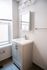 Bright modern bathroom with elegant white vanity, sleek mirror cabinet, and natural light from a large window.