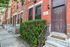 Inviting entrance of a charming red brick townhouse with lush greenery and classic architectural details, perfect for urban living.