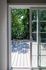 Inviting outdoor deck seen through a sliding glass door, surrounded by lush greenery for a serene ambiance.
