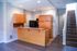 Charming kitchen with warm wooden cabinets, modern lighting, and elegant staircase in a bright, inviting space.