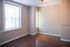 Bright apartment room with large window, elegant hardwood floors, and neutral-colored walls, perfect for a cozy and welcoming atmosphere.