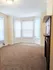 Sunlit apartment room with soft carpet flooring, classic bay windows, and an elegant fireplace.