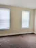 Bright and inviting room with neutral walls, plush carpeting, and natural light streaming through large windows.