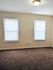 Bright room with plush carpeting, two large windows with blinds, and a modern ceiling light, perfect for creating a cozy atmosphere.
