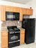 Modern kitchen with sleek black appliances, rich wooden cabinets, and elegant granite countertops.