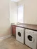 Bright laundry nook with modern washer and dryer, natural light streaming through a window above a stylish granite countertop.