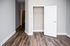 Bright, minimalist bedroom with smooth hardwood flooring and an open closet.