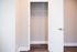 Bright and spacious walk-in closet with wooden flooring and sleek white door, perfect for modern living.