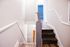 Bright and inviting stairway with sleek wooden flooring, leading to a modern room accented by elegant white trim.