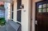Welcoming apartment entrance with a charming wooden door, illuminated by an elegant lantern and set in a quaint porch area with a cozy bench.
