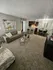 Inviting open-concept living area with cozy seating, modern decor, and a sleek breakfast bar adjacent to a stylish dining nook.