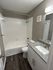 Modern bathroom featuring elegant granite countertops, sleek fixtures, and a combination shower-tub for a luxurious feel.