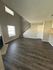 Bright and spacious living room with elegant dark wood flooring, a cozy corner fireplace, and stylish staircase leading to the upper level.