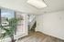 Bright and inviting interior with modern wood flooring, large windows with vertical blinds, and a stylish staircase enhancing the open living space.