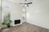 Bright living room with elegant wooden floors, modern ceiling fan, and a cozy fireplace enhanced by natural light streaming through large windows.