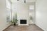Bright living room with high ceilings, large windows, elegant fireplace, and stylish flooring, featuring a cozy plant for a touch of nature.
