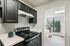 Charming kitchen with sleek black cabinets, modern stove, and bright dining nook overlooking lush greenery.