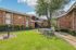 Charming brick apartment complex with lush green lawns, picnic tables, and a serene outdoor setting.