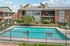 Charming apartment complex with a sparkling outdoor pool and vibrant landscaping, perfect for relaxing and leisure.