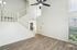 Bright and spacious living area with elegant wooden flooring, high ceilings, and a modern ceiling fan, featuring a stylish staircase.