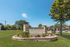 Inviting entrance of The Bridges on Travis, showcasing a well-maintained green lawn and elegant stone signage under a clear blue sky.