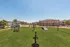 Charming community view with vibrant green lawn and modern apartments under a clear blue sky, highlighting ample parking and outdoor amenities.