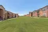 Charming apartment community view showcasing well-maintained green spaces and inviting two-story brick buildings under a clear blue sky.