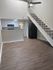 Bright and modern loft apartment with stylish wooden floors, sleek staircase, and compact kitchen featuring updated appliances.