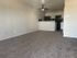 Charming open-concept living space with plush carpet, modern kitchen with sleek appliances, and a ceiling fan for comfort.