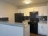 Modern kitchen featuring sleek black appliances, elegant white cabinets, and a stylish granite countertop with contrasting dark tile backsplash.