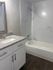 Elegant bathroom showcasing a luxurious bathtub, sleek granite countertop, and contemporary cabinetry with modern fixtures.