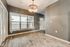 Bright modern apartment space showcasing sleek laminate flooring, a tasteful chandelier, and large windows inviting natural light.