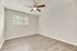 Bright and airy room with elegant wood flooring, a ceiling fan, and large window for natural light.