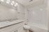 Elegant bathroom with sleek granite countertop, contemporary fixtures, and a luxurious marble-tiled bathtub surround.