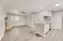 Bright and modern living area with stylish wood flooring, brick fireplace, and an open-concept kitchen featuring sleek cabinetry and mosaic backsplash.