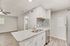 Modern open-concept apartment showcasing a chic kitchen with granite countertops, a mosaic backsplash, and stainless steel appliances seamlessly flowing into a bright living area with sleek hardwood floors and ceiling fan.